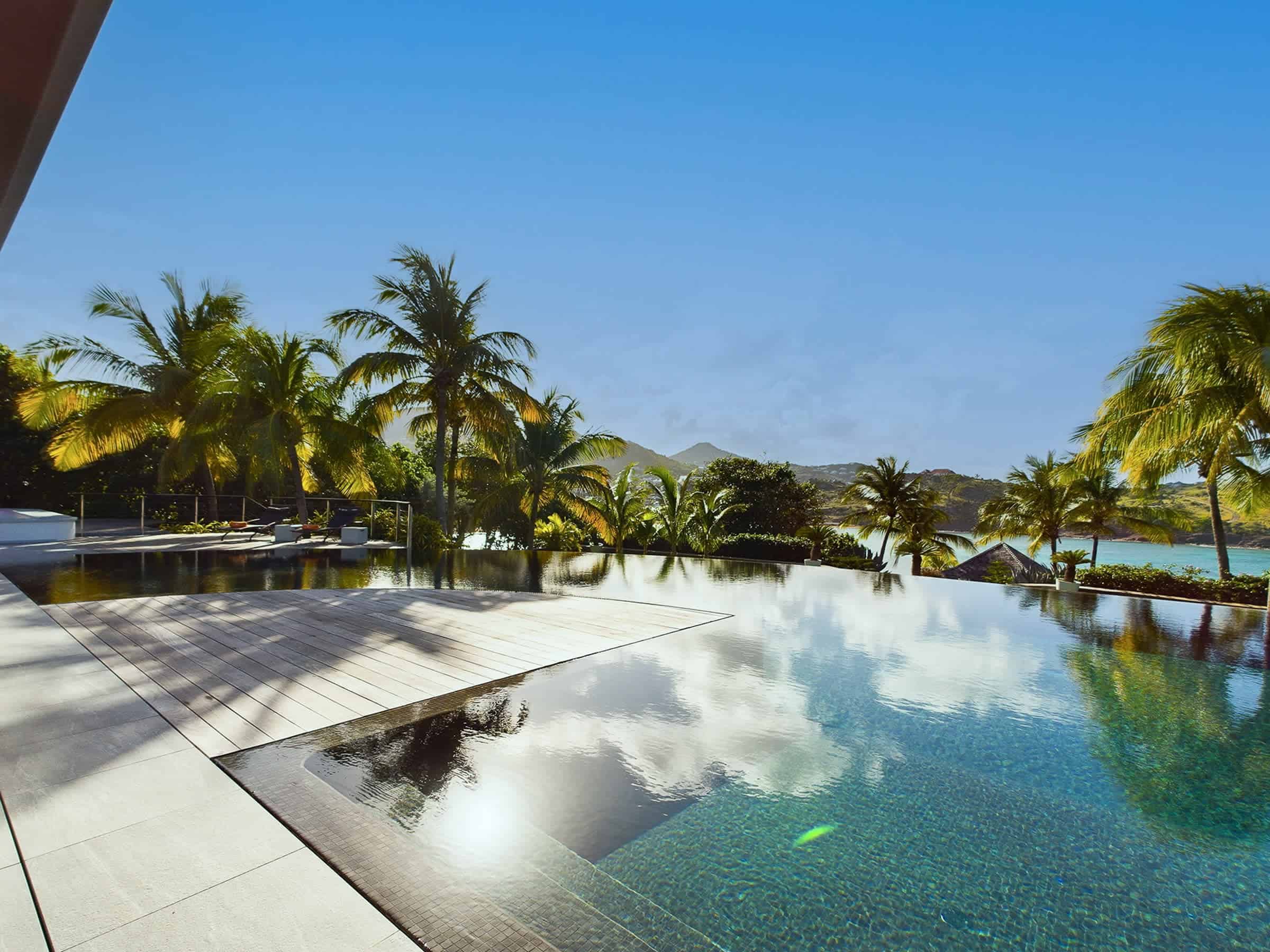 An infinity pool meets the bay, framed by swaying palms. A tranquil escape, embraced by nature.