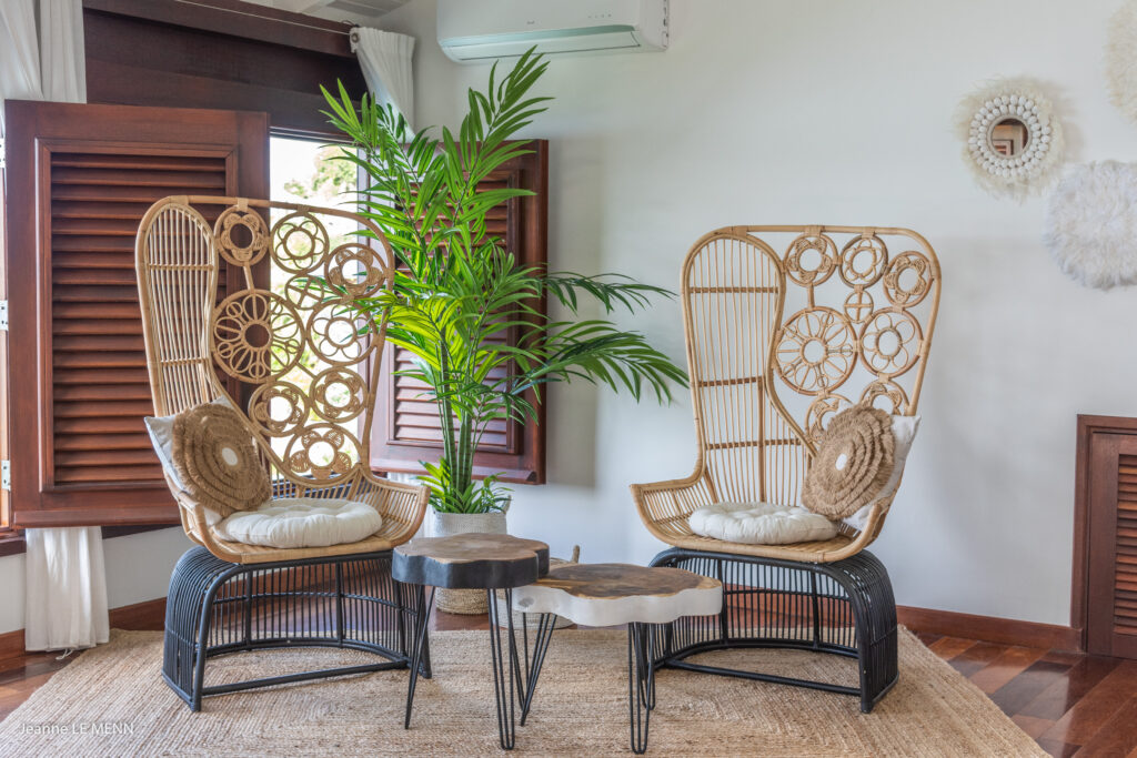 A beautifully designed eco-friendly interior in St. Barts, featuring handcrafted rattan chairs with intricate circular patterns, a natural fiber rug, and reclaimed wood tables. Earth-toned decor, tropical greenery, and sustainable materials create a serene and stylish island retreat.