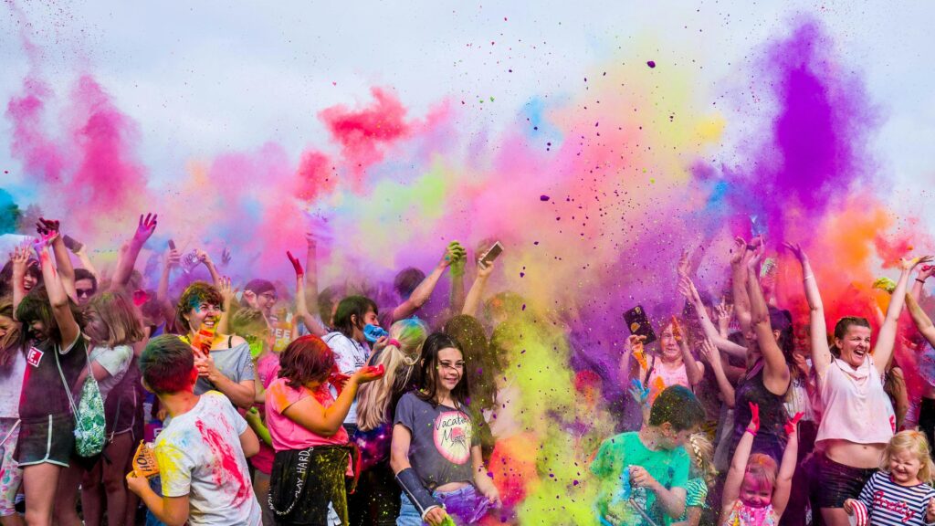 A vibrant cultural celebration in St. Barts, where a diverse crowd joyfully throws colorful powders into the air. The festival atmosphere is filled with energy, laughter, and a sense of community, reflecting the island’s dynamic and colorful spirit.