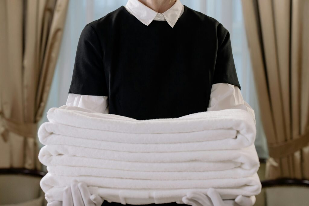 A staff member in St. Barts holding neatly folded white towels, representing the island's commitment to sustainable tourism through eco-friendly hospitality practices, including energy-efficient laundry services, reduced water consumption, and responsible waste management.